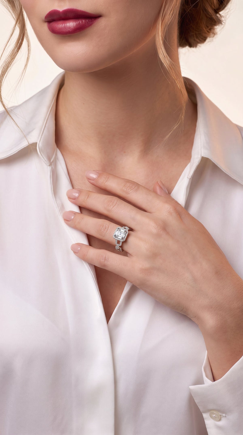 Woman in a white silk blouse wearing an Asscher cut moissanite halo engagement ring